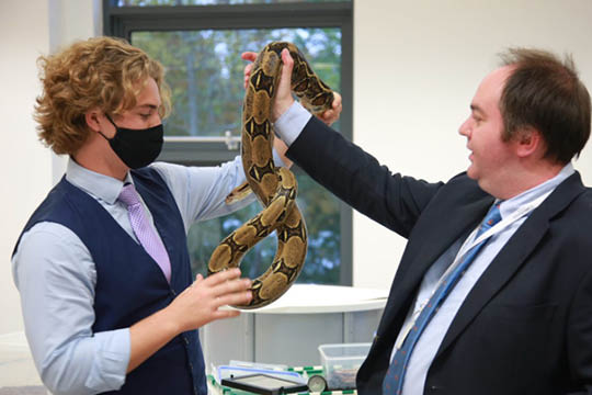 Sixth Form Student handling a snake during Crossing Borders Week - News